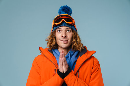 Caucasian tense sportsman posing with palms together on camera isolated over blue backgroundの写真素材