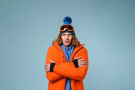 Caucasian displeased sportsman shaking and trembling from cold isolated over blue backgroundの写真素材