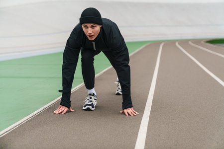 Young athletic runner man doing exercise while working out at stadium outdoors