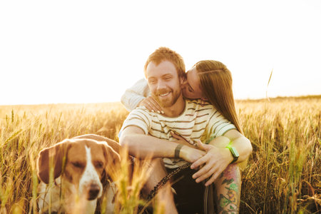 Image of a young happy cheery loving couple hugging outside at the field near dogの写真素材