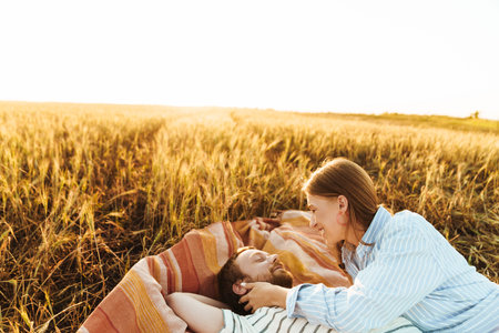 Image of a young cheery happy loving couple lying together outside at the fieldの写真素材