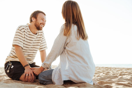 Image of a young happy loving couple sitting outside at the beachの写真素材