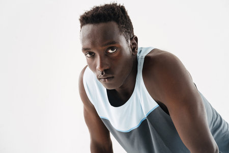 Young athletic african american sportsman posing and looking at camera isolated over white...