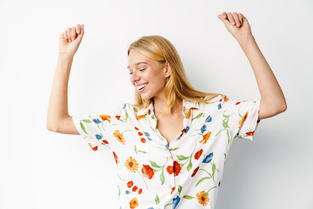 Happy beautiful girl smiling and dancing at camera isolated over white backgroundの写真素材
