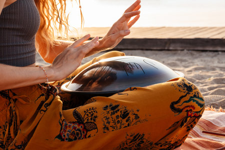Cropped photo of young woman playing music on drum at the beachの写真素材