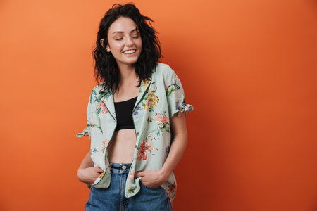 Pretty young smiling happy woman isolated over orange wall background