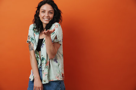 Pretty young happy woman isolated over orange wall background blowing kissesの写真素材