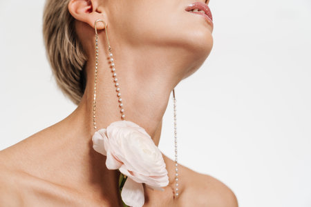 Sensual shirtless girl wearing earrings posing with flower isolated over white backgroundの写真素材