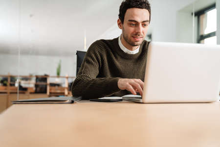 Smiling entrepreneur working with a laptop and documents in an officeの写真素材