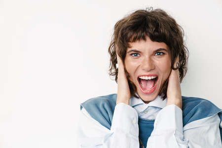 Excited beautiful girl screaming and covering her ears isolated over white background