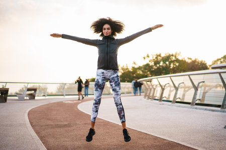 Young athletic sportswoman doing exercise while working out on city bridgeの写真素材