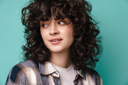 Caucasian beautiful curly girl posing and looking aside isolated over blue background