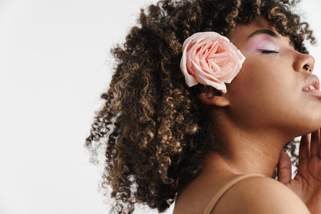 Beautiful sensual african american girl with rose posing at camera isolated over white backgroundの写真素材