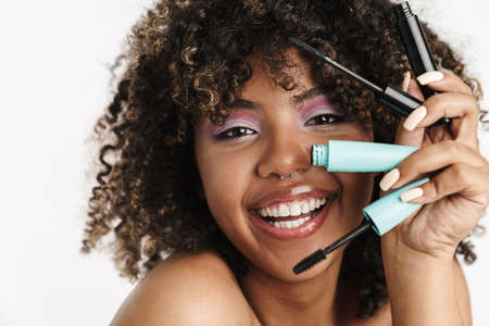 Beautiful joyful african american girl posing with mascara isolated over white backgroundの写真素材