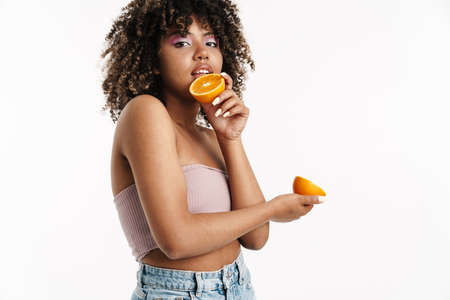 Beautiful nice african american girl posing with orange isolated over white background