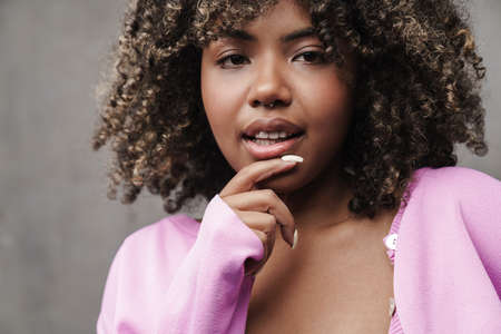 Beautiful african american woman posing and looking at camera isolated over grey wallの写真素材