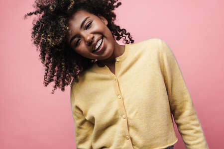 Happy african american woman posing and laughing at camera isolated over pink wall