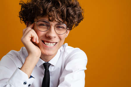 Happy male student standing wearing uniform isolated on a yellow backgroundの写真素材