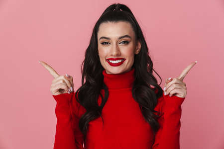 Beautiful woman pointing sideways isolated over pink backgroundの写真素材