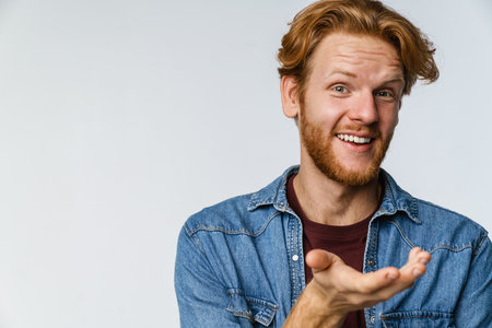 Joyful handsome guy smiling and holding copyspace isolated over white background