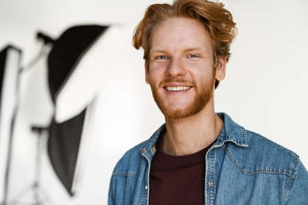 Happy handsome ginger guy smiling and looking at camera in studio indoorsの写真素材