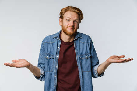 Pleased unshaven redhead guy posing and looking at camera isolated over white backgroundの写真素材