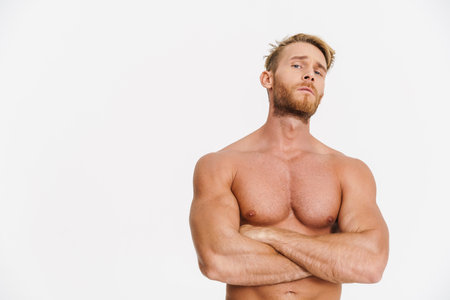 Handsome caucasian shirtless man posing with arms crossed isolated over white backgroundの写真素材