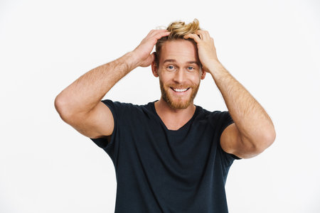 Cheerful caucasian blonde man posing and smiling at camera isolated over white backgroundの写真素材
