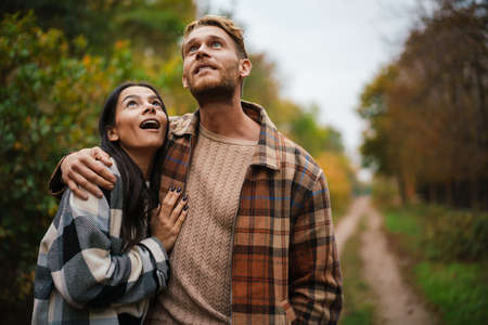 Beautiful happy couple smiling and hugging while strolling in autumn forest
