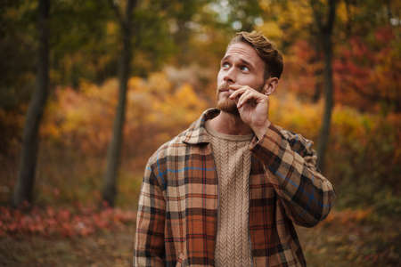 Handsome redhead unshaven man strolling in autumn forest