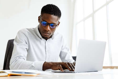 Thoughtful young african american businessman working on laptop computerの写真素材