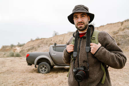Focused handsome photographer walking with digital camera outdoors