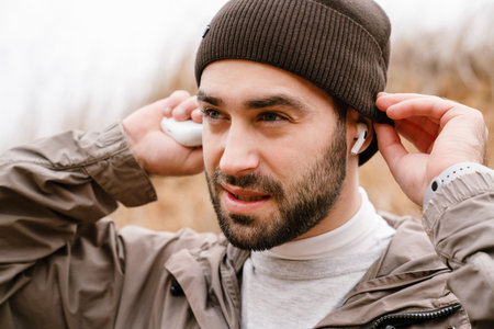 Young serious sportsman in wireless earphones working out in natureの写真素材