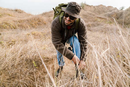 Happy handsome photographer in sunglasses walking with digital camera outdoorsの写真素材