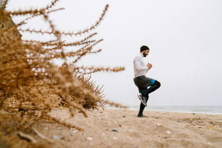 Confident young sportsman exercising at the beach, wearing war, clothesの写真素材