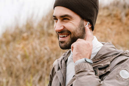 Young happy sportsman in wireless earphones laughing while working out in natureの写真素材