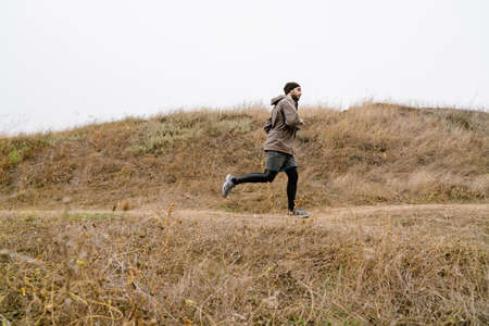Young focused sportsman running while working out in nature