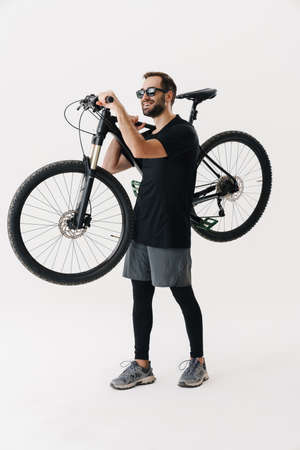 Happy young rider man smiling while posing with his bicycle isolated over white backgroundの写真素材