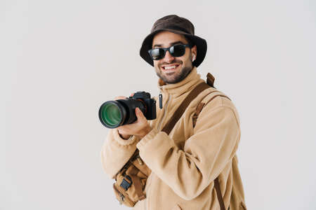 Excited photographer in earphones taking photo on digital camera isolated over white backgroundの写真素材