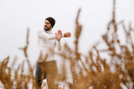 Confident young sportsman exercising at the beach, wearing war, clothesの写真素材