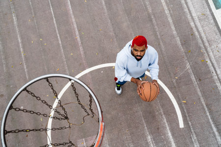 Bearded african american guy in earphones playing basketball at playground outdoorsの写真素材
