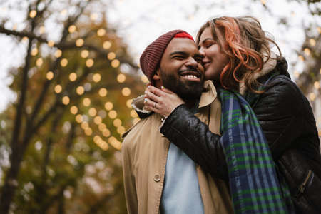 Multinational beautiful happy couple hugging and laughing while walking on city street