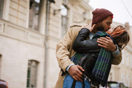 Multinational romantic happy couple kissing and hugging at city street