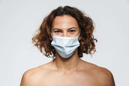 Pleased caucasian shirtless guy posing in protective mask isolated over white backgroundの写真素材