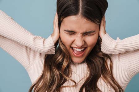 Excited beautiful nice girl screaming and grabbing her head isolated over blue backgroundの写真素材