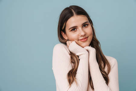 Happy beautiful girl posing and smiling at camera isolated over blue background