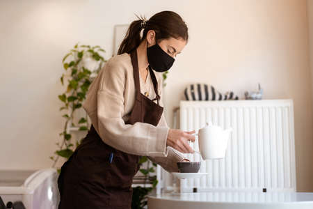 Waitress in a medical protective mask serves coffee in the cafeの写真素材