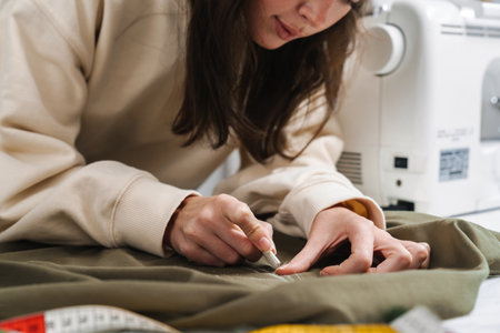Portrait of concentrated seamstress sewing in the workshop studio, close upの写真素材