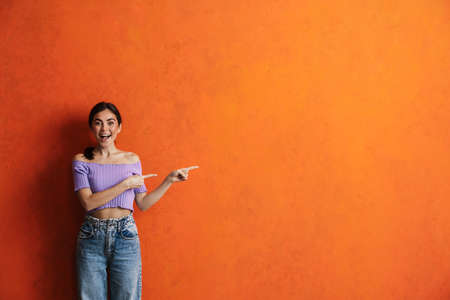 Portrait of cheerful young woman prsenting copy space while standing over isolated backgroundの写真素材