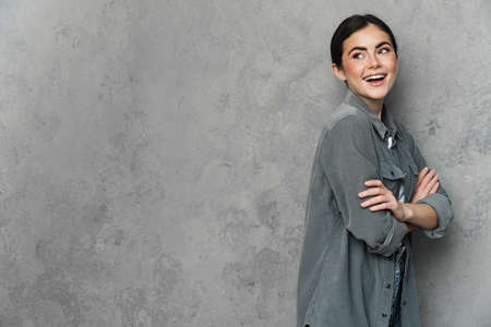 Portrait of happy smiling woman dressed in casual wear standing over isolated background, posing